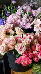 Close-up view of assorted fresh flowers in a florist shop, featuring pastel pink roses surrounded by colorful blooms such as hydrangeas, daisies, and tulips