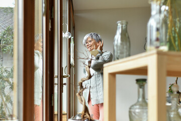 A 75-year-old gray-haired woman looks out the window