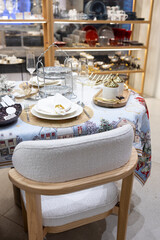 A beautifully set table for a festive event. Two lighted candles, elegant glassware and decorative ornaments are placed near the Christmas tree.