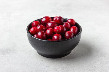 Shiny red cranberries in dark bowl