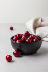 Fresh cranberries in black bowl with linen napkin