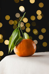 Fresh tangerine with green leaves and festive bokeh lights
