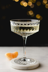 Crystal champagne glass with marble coaster and tangerine slice