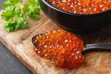 Red salmon caviar on a spoon with parsley close up