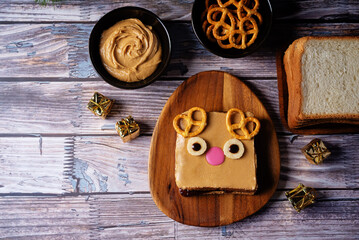 Berry jam peanut butter sandwich in the form of deer for Christmas holidays on a wood background