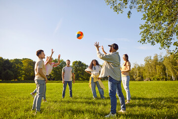 Company of friends play ball outdoors in city park during holiday or party, enjoying weekend leisure, fostering a festive atmosphere in a public space filled with fun and shared celebration moments.