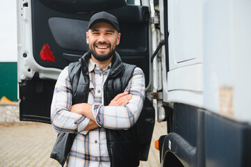 Happy truck driver standing with arms crossed next to cargo truck