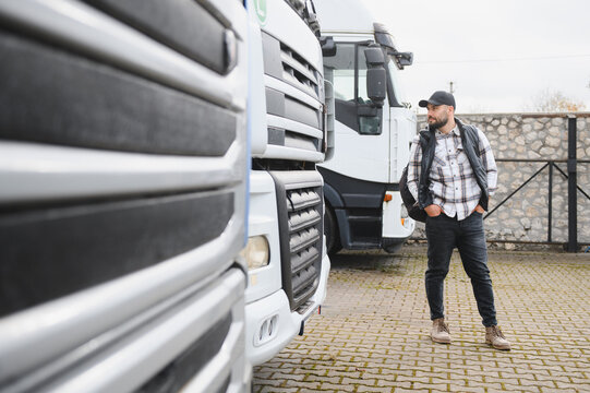 Truck driver man standing beside semi trucks