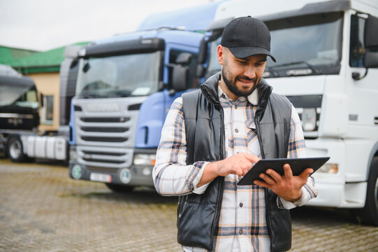 Truck driver managing logistics using tablet computer at fleet terminal