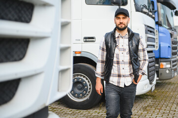 Truck driver standing confident near semi trucks