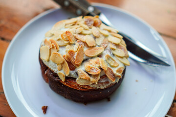 A delicious almond pastry on a white plate is ready to be enjoyed.  The flaky crust and sweet almonds create an irresistible treat. A perfect image for food publications and dessert promotions.