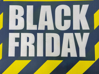 close-up of black friday white bold text on dark background with yellow chevron stripes significant empty space for text banner concept of retail sales, e-commerce, shopping deals
