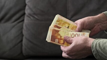 separate Israeli new shekel banknotes from a stack and give them as cash payment. Currency money physical transfer NIS denomination in a close-up view