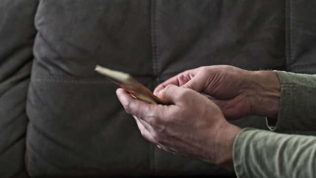 man's hand is captured collecting a fan of cash  New Israeli Sheqel banknotes from a prior financial transaction. The hand then makes an aggressive gesture,  larger sum of the local NIS currency.