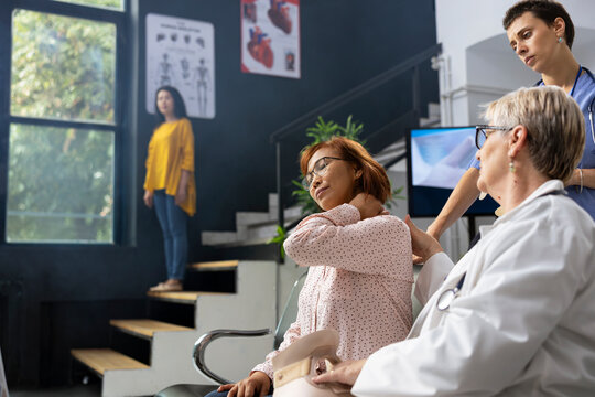 Healthcare professional checking on woman with neck pain and shoulder strain during routine wellness checkup. Reducing pressure and avoiding acute stress injuries through proper posture.