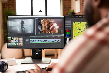 African american video editor working with dual monitors to assemble raw footage and make creative...