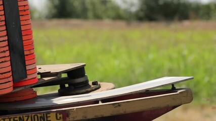 Close-up of an automatic clay pigeon thrower loaded with orange targets, ready to launch disks into the field for trap shooting sport practice on a sunny summer day.
