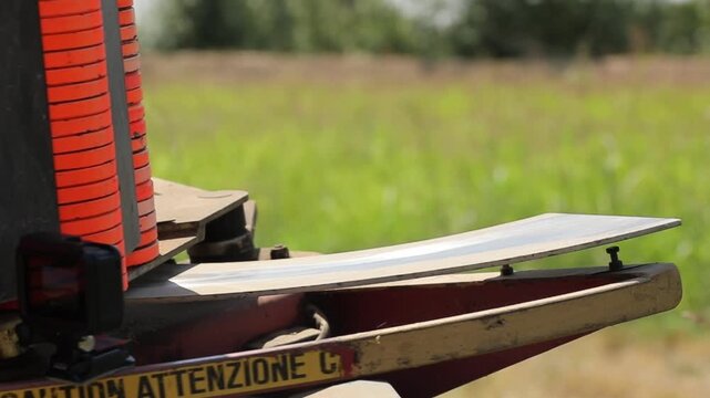 Close-up of an automatic clay pigeon thrower loaded with orange targets, ready to launch disks into the field for trap shooting sport practice on a sunny summer day.