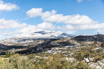 Mountains and trees covered in snow under bright blue sky and clouds after a California snowfall