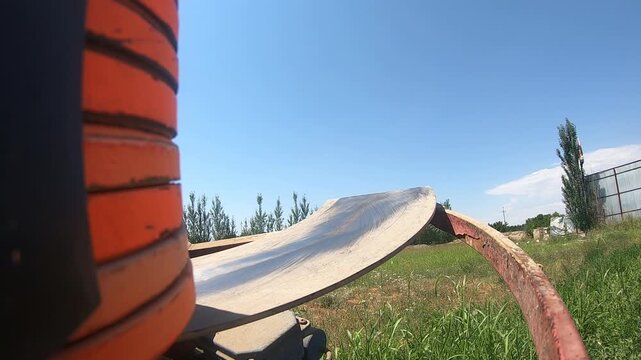 Close-up of an automatic clay pigeon thrower loaded with orange targets, ready to launch disks into the field for trap shooting sport practice on a sunny summer day.
