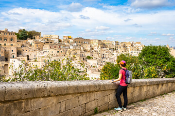 Female tourist admiring the stunning cityscape of Matera from a scenic viewpoint on a bright day,...