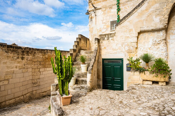 Rustic stone courtyard with potted cacti and old green doors in Matera&rsquo;s old town, Apulia, Italy