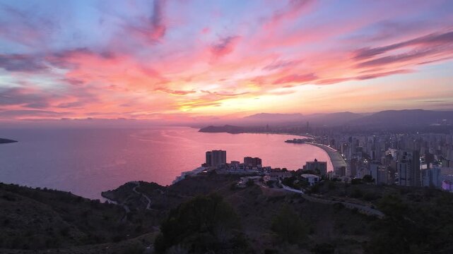 Benidorm skyline at sunset with vivid clouds and soft light reflecting over the Mediterranean, captured from an elevated viewpoint.