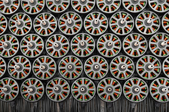 numerous brushless FPV drone motors closely packed. internal copper windings are clearly visible through the open gray stator bells