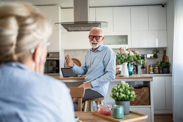 Senior couple talking in kitchen showing modern lifestyle