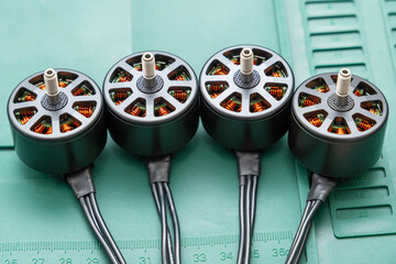 brushless FPV drone motors is arranged linearly on a green mat, motors feature visible copper windings within the dark gray stators, and three black wires extend neatly from the base