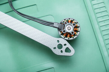 brushless FPV drone motor sits next to a matching carbon fiber motor arm with pre-drilled mounting holes