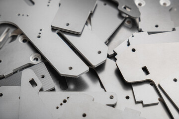 dense pile displays numerous thin, precision-cut carbon fiber composite parts scattered randomly, used as structural plates for high-performance FPV drone frame