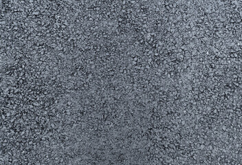 rough texture of a newly laid asphalt surface, filling the entire frame with a dark gray granular composition. The freshly paved road material durable layer.