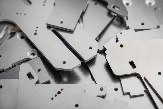 dense pile displays numerous thin, precision-cut carbon fiber composite parts scattered randomly, used as structural plates for high-performance FPV drone frame