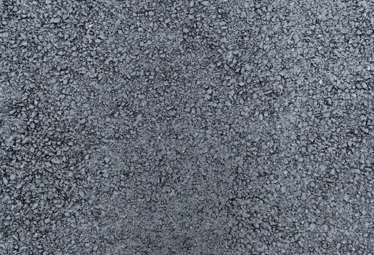 rough texture of a newly laid asphalt surface, filling the entire frame with a dark gray granular composition. The freshly paved road material durable layer. - Powered by Adobe