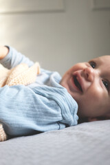 A heartwarming close-up of a smiling newborn baby lying on a soft surface and wrapped in a cozy knitted blanket.