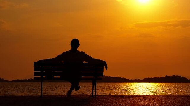 Man tourist silhouette on dusk amazing beach. A cute man silhouette admire the amazing sunset by the sea in summer
