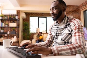 African American man typing on computer keyboard and updating his online journal and researching...