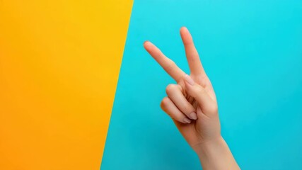 Hand gesturing peace sign against blue and yellow background Caucasian female - Powered by Adobe