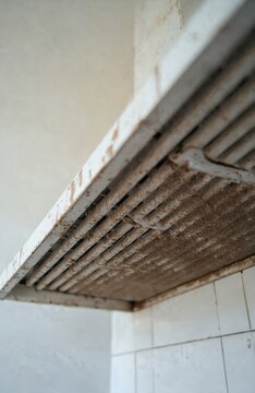 Close up photo of dirty kitchen hood vent. Over head view shows old dust covered metal grille. Visible dirt and debris on the residential appliance filter.