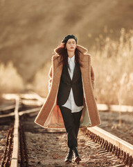 Elegant fashionable lady in brown fur coat over classic business suit on background of country autumn landscape