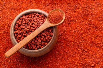 Crushed annatto seeds in the spoon and in the bowl - Bixa Orellana