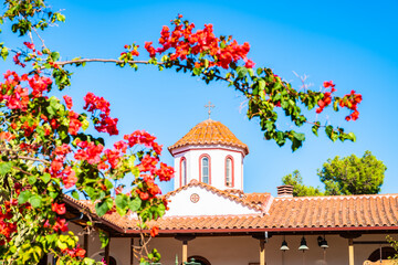 Tower of chapel in old historic Faneromeni monastery with flowers in foreground, Lefkada island, Greece