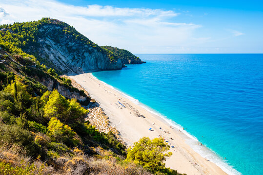 View of cliffs with green pine trees and Milos beach from high vantage point, Lefkada island, Greece