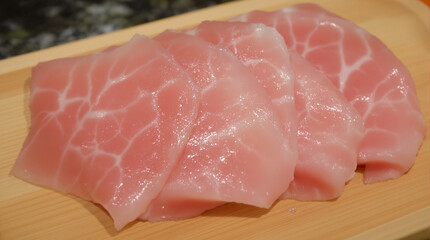 Close-up view of fresh, raw tuna sashimi slices arranged on a wooden serving board.