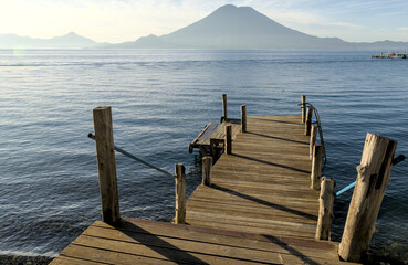 wooden dock pier at lake atitlan in guatemala (volcanic caldera crater) deepest lake in central america morning light beautiful relaxing travel destination blue turquoise water volcano view santa cruz