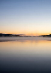 Obraz premium Ethereal tranquility over water as dawn breaks painting the horizon with pastel hues and lingering fog