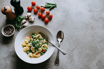 Enjoy a delicious bowl of pasta with peas and tomatoes, perfect for a healthy lunch or dinner with fresh ingredients in a cozy setting, inviting you to savor simple pleasures