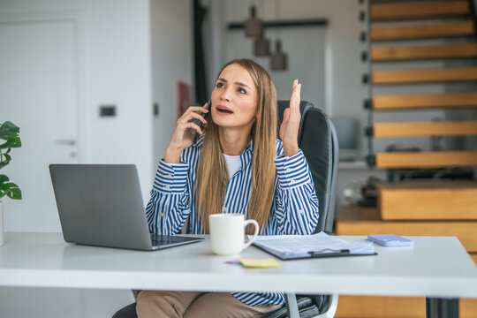 Stressed woman talking on phone working online from home office - Powered by Adobe