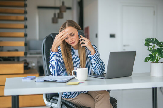 Stressed woman talking on phone working online from home office
